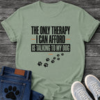 Bold graphic tee design reading "The Only Therapy I Can Afford Is Talking to My Dog," with orange accent lines and a trail of paw prints below.