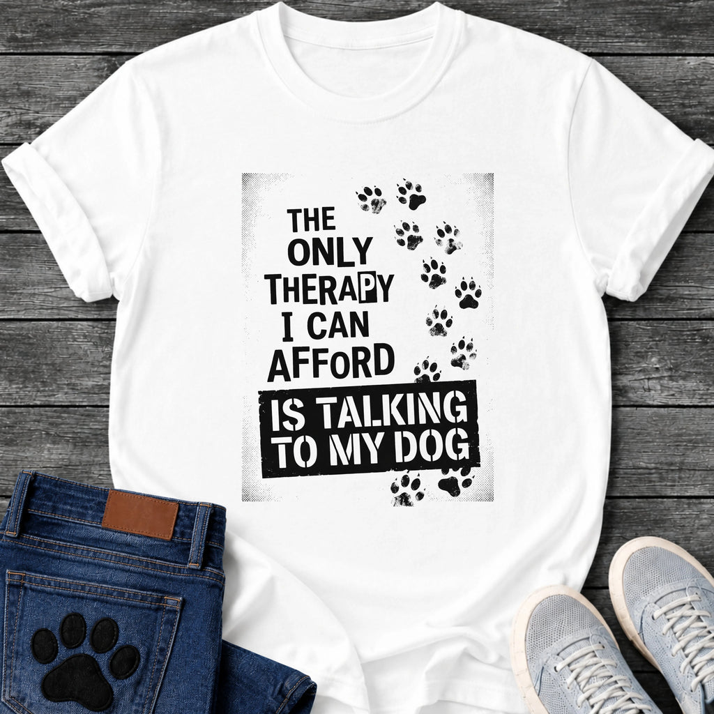 Bold stamped graphic tee design reading "The Only Therapy I Can Afford Is Talking to My Dog," with a trail of paw prints climbing the side.