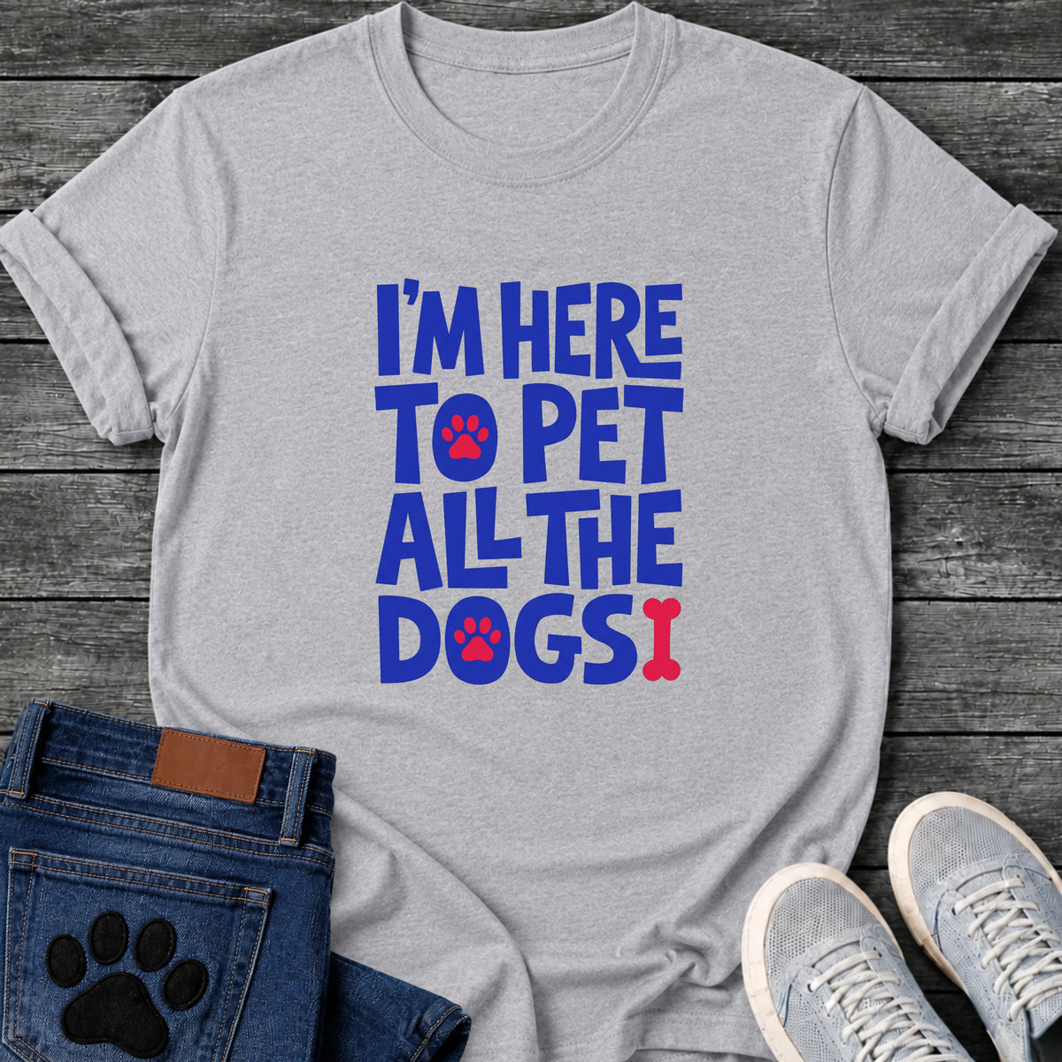 Im Here To Pet All The Dogs t shirt design in bold blue bubble letters with red paw prints and a bone shaped exclamation point