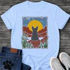 French Bulldog t-shirt with Frenchie silhouette seen from behind sitting on contoured red rock, large gold sun against slate blue sky, red canyon walls on either side, forest green ferns in foreground, distressed woodcut border frame, no text national park style art graphic