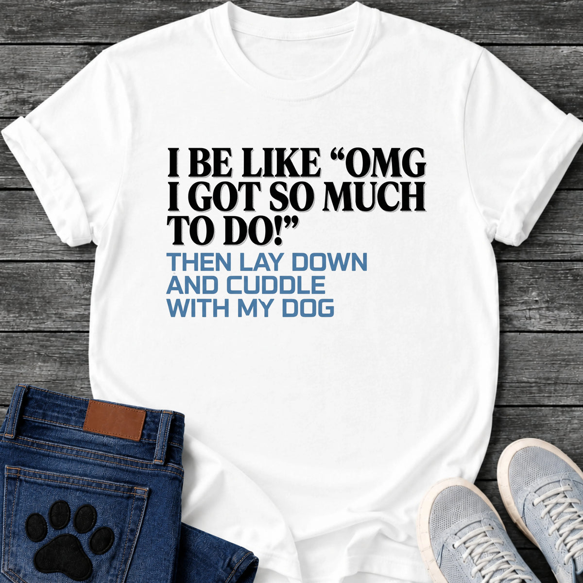 Bold two tone graphic tee design reading "I Be Like 'OMG I Got So Much To Do!' Then Lay Down and Cuddle With My Dog" in black and blue lettering.