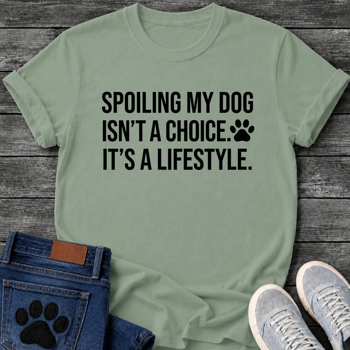 Bold graphic tee design reading "Spoiling My Dog Isn't a Choice, It's a Lifestyle," with a small paw print beside the text.
