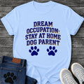 Collegiate style varsity graphic tee design reading "Dream Occupation: Stay at Home Dog Parent," with two paw prints below the text.