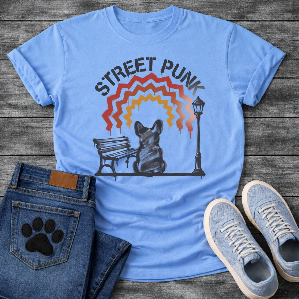 French Bulldog t-shirt with stencil arched text reading Street Punk above a spray paint scene of a Frenchie sitting on a park bench beside a street lamp, zigzag spray paint rainbow in red terracotta and gold with drips, urban street art graphic