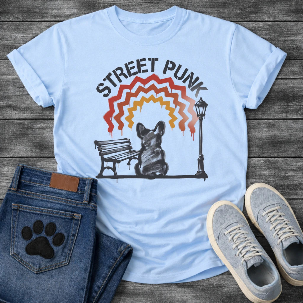 French Bulldog t-shirt with stencil arched text reading Street Punk above a spray paint scene of a Frenchie sitting on a park bench beside a street lamp, zigzag spray paint rainbow in red terracotta and gold with drips, urban street art graphic