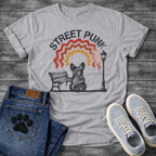 French Bulldog t-shirt with stencil arched text reading Street Punk above a spray paint scene of a Frenchie sitting on a park bench beside a street lamp, zigzag spray paint rainbow in red terracotta and gold with drips, urban street art graphic