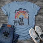 French Bulldog t-shirt with stencil arched text reading Street Punk above a spray paint scene of a Frenchie sitting on a park bench beside a street lamp, zigzag spray paint rainbow in red terracotta and gold with drips, urban street art graphic