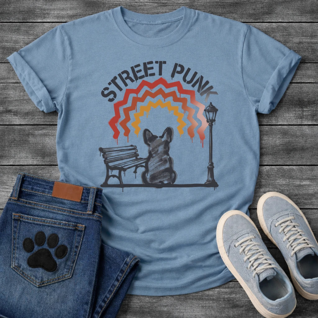 French Bulldog t-shirt with stencil arched text reading Street Punk above a spray paint scene of a Frenchie sitting on a park bench beside a street lamp, zigzag spray paint rainbow in red terracotta and gold with drips, urban street art graphic