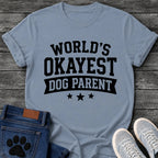 Varsity style graphic tee design reading "World's Okayest Dog Parent," with a banner ribbon and three stars underneath.